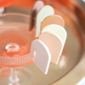 different color arch drink markers on a pink cocktail coupe