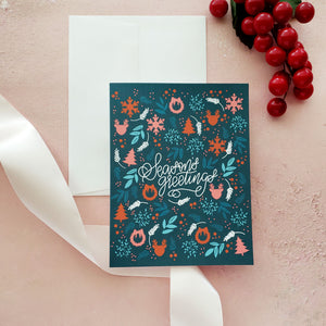 dark teal hoiliday greeting card with pink and red wintry illustrations and handlettered script