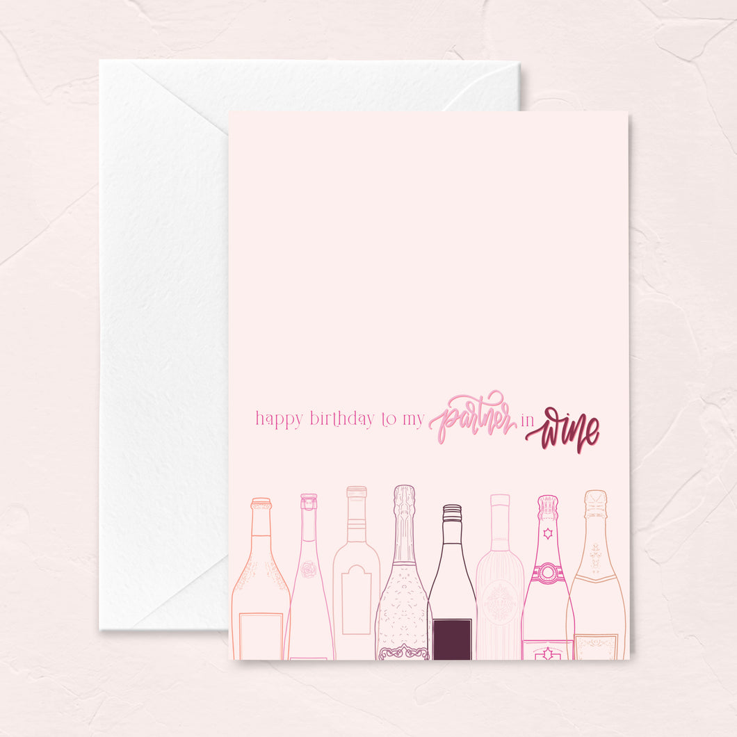 birthday greeting card for wine lovers with a light pink background, wine bottle illustrations and the words happy birthday to my partner in wine