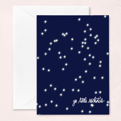 graduation greeting card with a navy blue sky and sparkly star pattern that says go little rockstar in script at the bottom