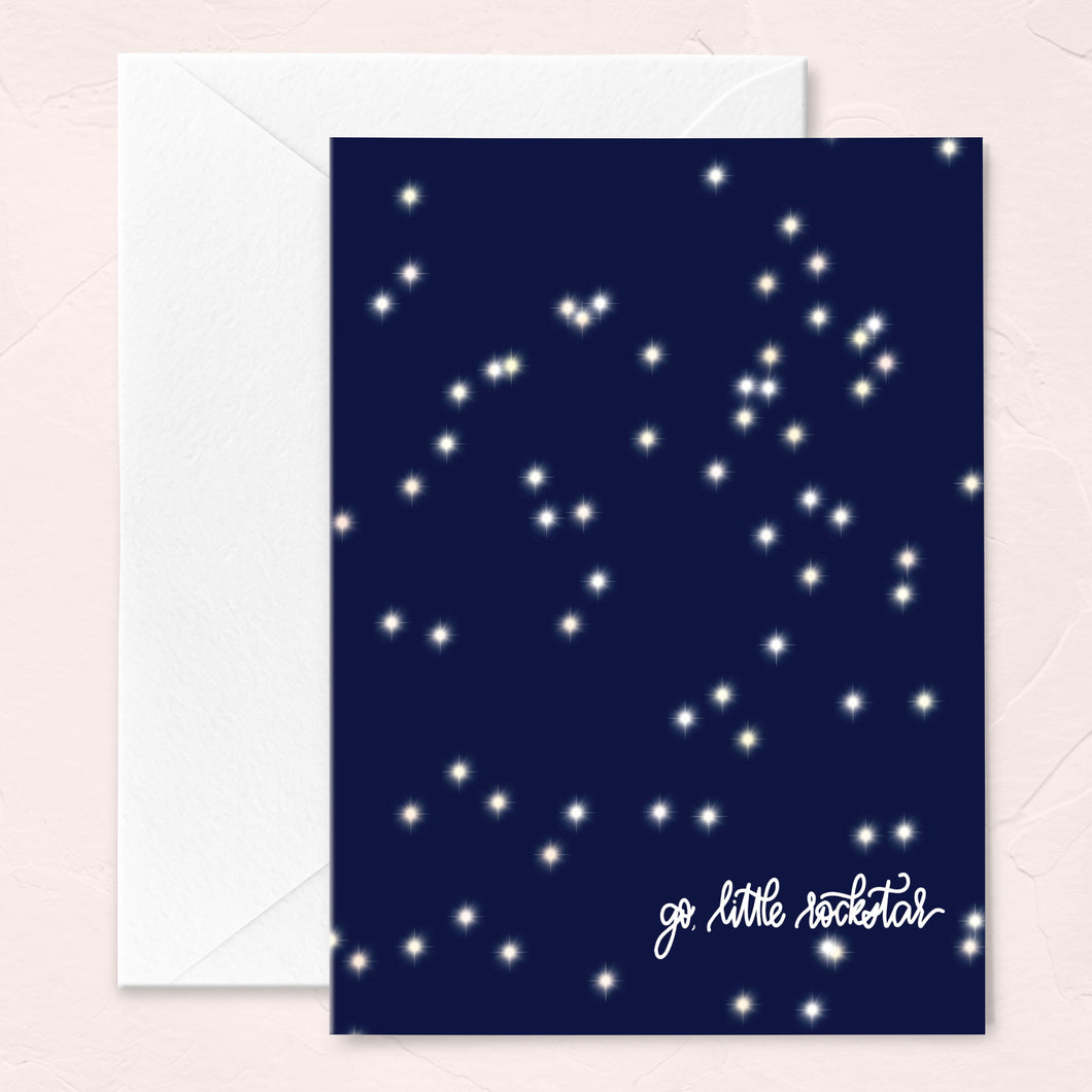 graduation greeting card with a navy blue sky and sparkly star pattern that says go little rockstar in script at the bottom